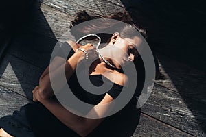 Top view portrait of beautiful sexy girl in black dress lying on wooden floor