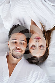 Top view portrait of cheerful, romantic couple in love, lying on bed with smile