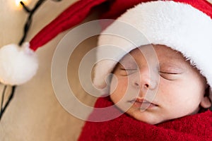 Top View Portrait First Days Life Newborn Cute Funny Sleeping Baby In Santa Hat Wrapped In Red Diaper At White Garland