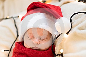 Top View Portrait First Days Of Life Newborn Cute Funny Sleeping Child Baby In Santa Hat Wrapped In Red Diaper At White