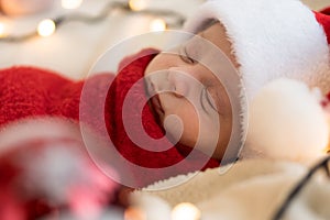 Top View Portrait First Days Of Life Newborn Cute Funny Sleeping Child Baby In Santa Hat Wrapped In Red Diaper At White