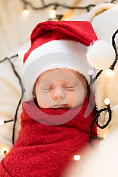 Top View Portrait First Days Of Life Newborn Cute Funny Sleeping Child Baby In Santa Hat Wrapped In Red Diaper At White