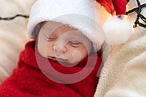 Top View Portrait First Days Of Life Newborn Cute Funny Sleeping Child Baby In Santa Hat Wrapped In Red Diaper At White