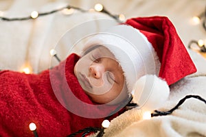 Top View Portrait First Days Of Life Newborn Cute Funny Sleeping Child Baby In Santa Hat Wrapped In Red Diaper At White