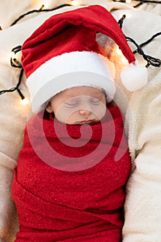Top View Portrait First Days Of Life Newborn Cute Funny Sleeping Child Baby In Santa Hat Wrapped In Red Diaper At White