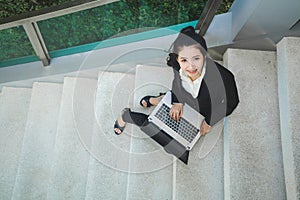 Top view portrait happy business woman in black suit sitting at