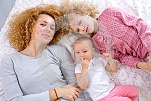 Top view portrait of a happy mother and her children lying on a bed