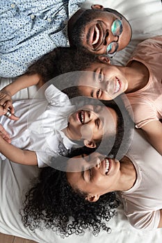 Top view portrait laughing african family lying down on bed