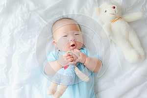 Top view Portrait of a newborn Asian cute baby boy wore blue Infant bodysuit on the bed , Charming Fat baby 5 month old lies in