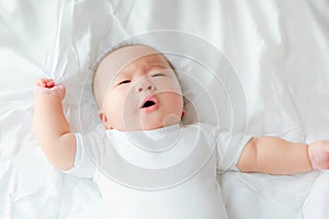 Top view Portrait of a newborn Asian cute baby boy wore white Infant bodysuit on the bed , Charming Fat baby 5 month old