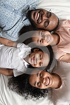 Top view portrait of smiling black family lying on bed