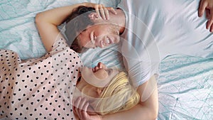 Top view portrait of young lovers lying in bed face to face bonding