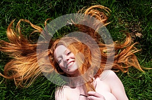 Top view portrait of young sexy beautiful redhead woman, happy content laughing relaxing, lying in the spring, summer sun, the red