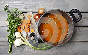 Top view on pot of tomato soup and fresh vegetables