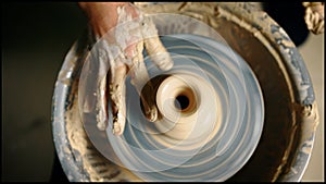 Top view of potter hands working on pottery wheel and making a pot