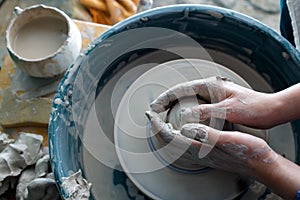 Top view of the potter`s hands. a clay master creates a product on a potter`s wheel