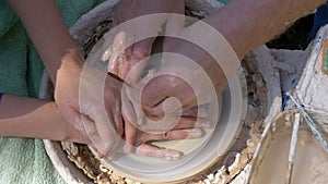 Top view on Potter`s hands work with clay on a potter`s wheel
