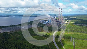 Top view of power plant on lake shore. Clip. Factory pipes on background of lake and green forest. Landscape with power