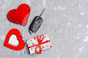 Top view of a present for Valentine`s Day on wooden background. Car key, gift box and heart with copy space. Surprise concept for