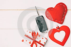 Top view of a present for Valentine\'s Day on wooden background. Car key, gift box and heart with copy space. Surprise concept for