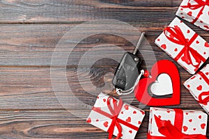 Top view of a present for Valentine`s Day on wooden background. Car key, gift boxes and heart with copy space. Surprise concept