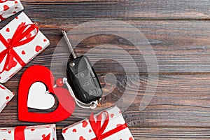 Top view of a present for Valentine\'s Day on wooden background. Car key, gift boxes and heart with copy space. Surprise concept