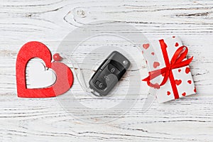 Top view of a present for Valentine`s Day on wooden background. Close up of car key, gift box and heart. Surprise concept for a