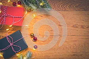 Top view of presents, pine tree branches, Christmas balls and lights on wooden background