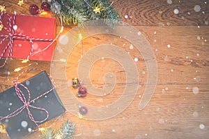 Top view of presents, pine tree branches, Christmas balls and lights on wooden background with snow overlay