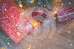 Top view of presents, pine tree branches, Christmas balls and lights on wooden background with snow overlay