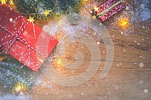 Top view of presents, pine tree branches, Christmas balls and lights on wooden background with snow overlay