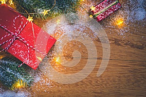 Top view of presents, snow, pine tree branches, Christmas balls and lights on wooden background