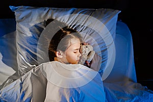 Top view. The pretty teen girl naps with a plush toy, sees a pleasant sleep.