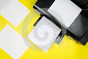 Top view of the printer and blank sheets of paper on a yellow background