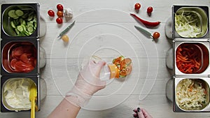 Top view of professional chef cooks a delicious burger at fast food restaurant. Female chef in gloves puts solt on