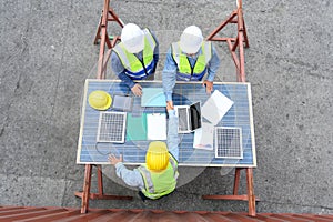 Top view of professional engineering people wearing helmets and safety vests meeting with solar photovoltaic panels handshake for