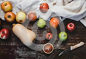 top view of pumpkin, apples, blood oranges, kitchen towel and knife