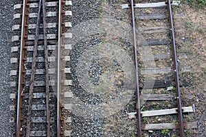 Top view of railway tracks in the countryside. Close-up of the railroad. Rusty iron train railway detail on gravel background