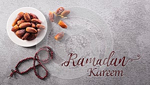 Top view of Ramadan Kareem decoration, dates fruit, rosary beads and the text on dark stone background