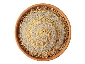 Top view of raw brown rice also called hulled rice, unpolished rice,husked rice on wooden bowl isolated on white background.