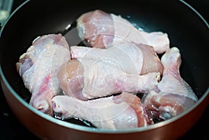 Top view, raw chicken legs are fried in a frying pan on an electric stove. concept of a menu of chicken legs raw meat. Meat ingr