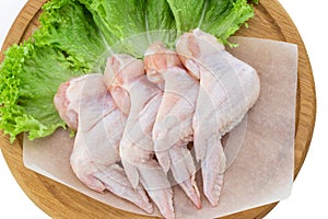 Top view of raw chicken wings on wooden cutting board isolated on white background