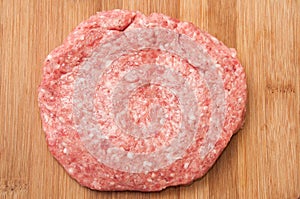 Top view of raw hamburger on wooden board prepared for roasting