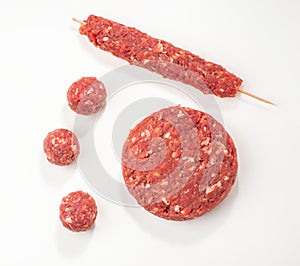 Top view on raw meatballs, patty and kebab on white background