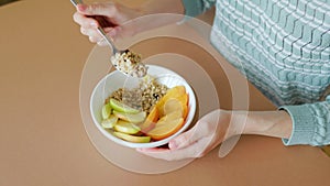 Top view raw oats, mango natural bowl and spoon in woman hands.