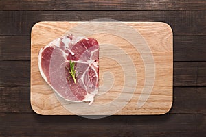 Top view raw pork chop steak on cutting board on wooden background.