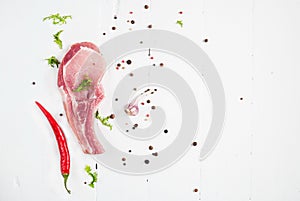 Top view raw pork chop steak and garlic, chili pepper on white wooden background