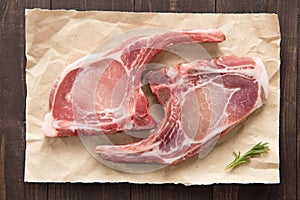 Top view raw pork chop steak on paper on wooden background