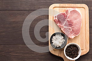 Top view raw pork chop steak and salt, pepper on wooden backgrou