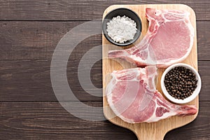 Top view raw pork chop steak and salt, pepper on wooden background